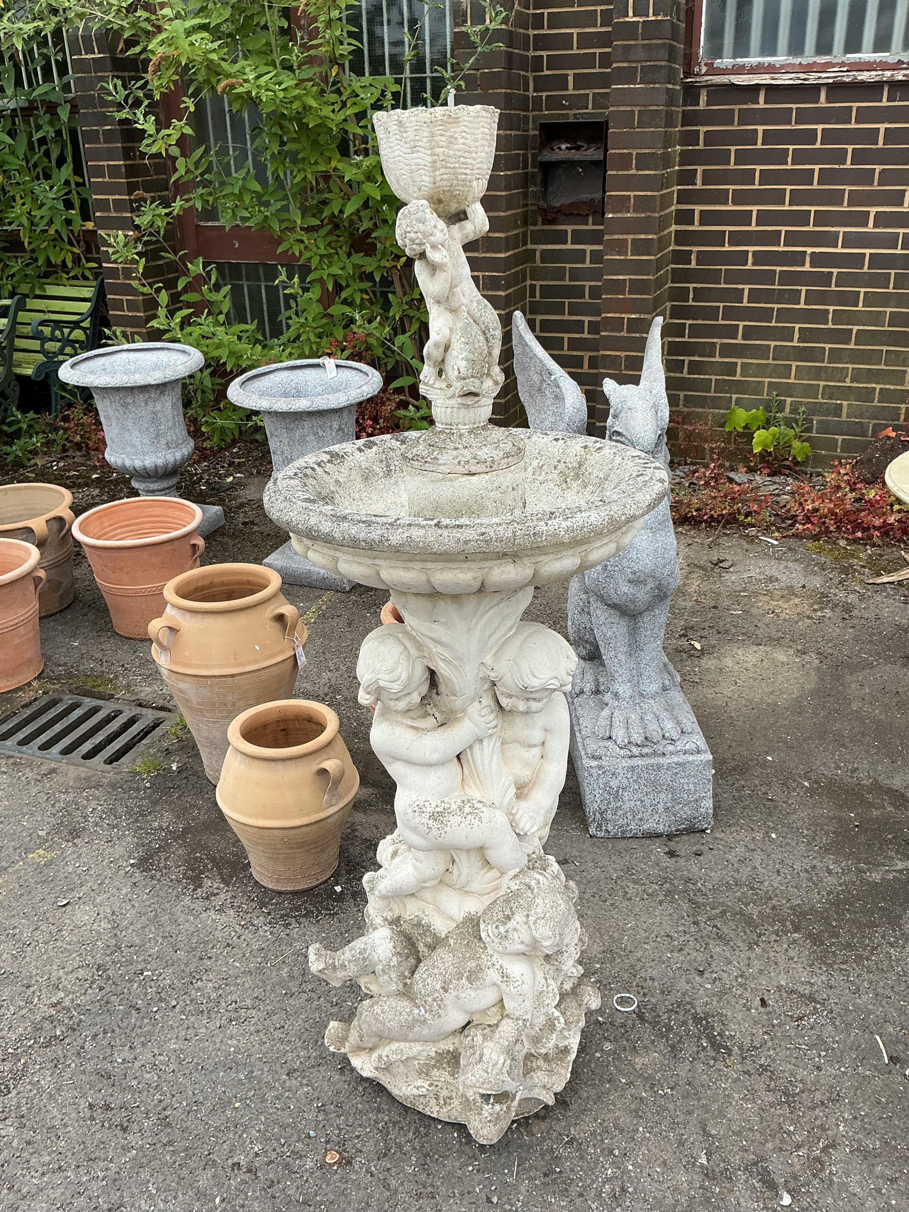 A reconstituted stone cherub and dolphin garden fountain, height 134cm